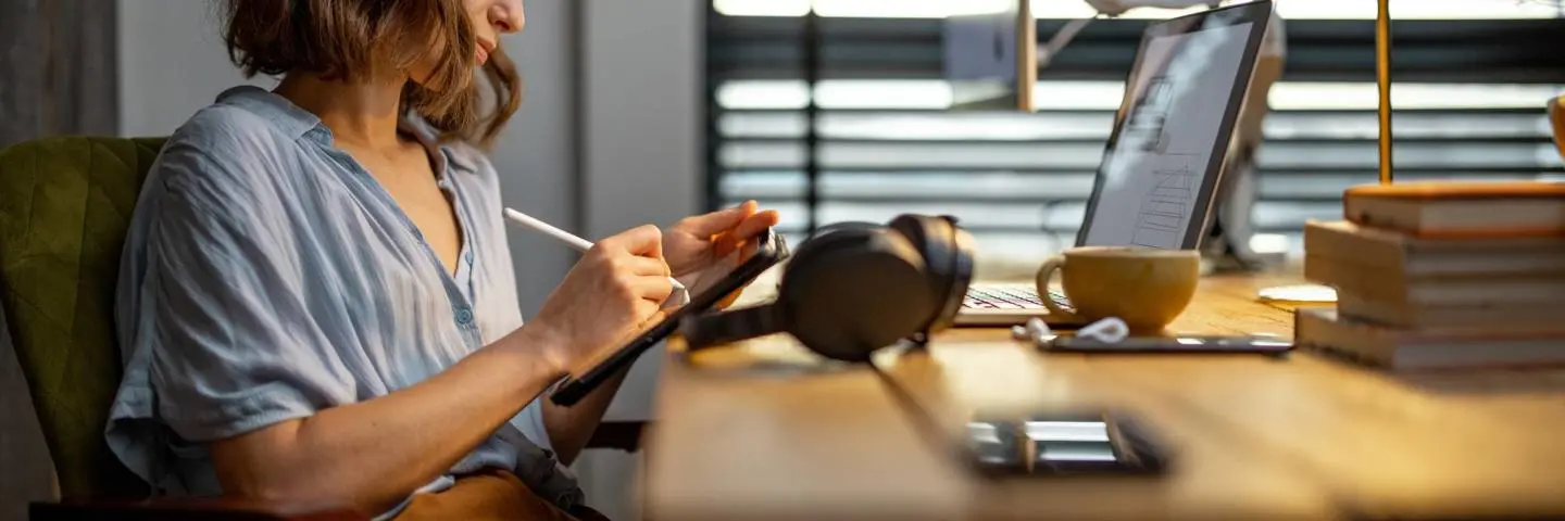 A woman writes on a drawing pad at a desk in an office