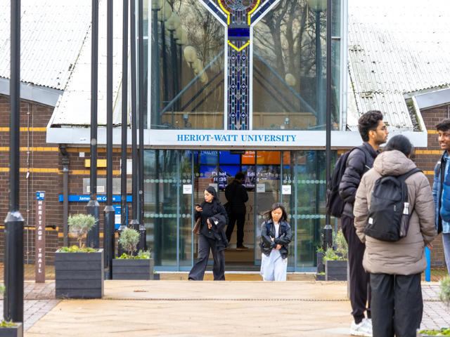 Individuals standing at an entrance to a building.