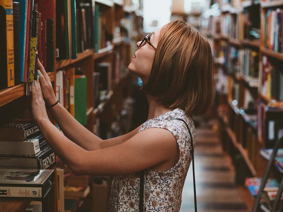 A woman looks at the rows of books in a bookshop