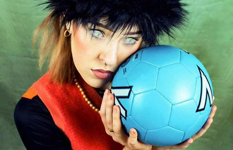 head shot of girl with green edited eyes holding a blue ball next to her face