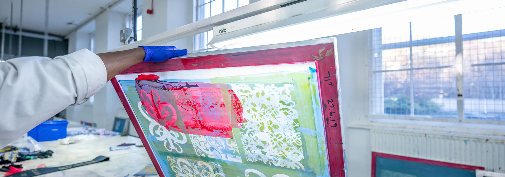 An individual holds up a red and green print under the light.
