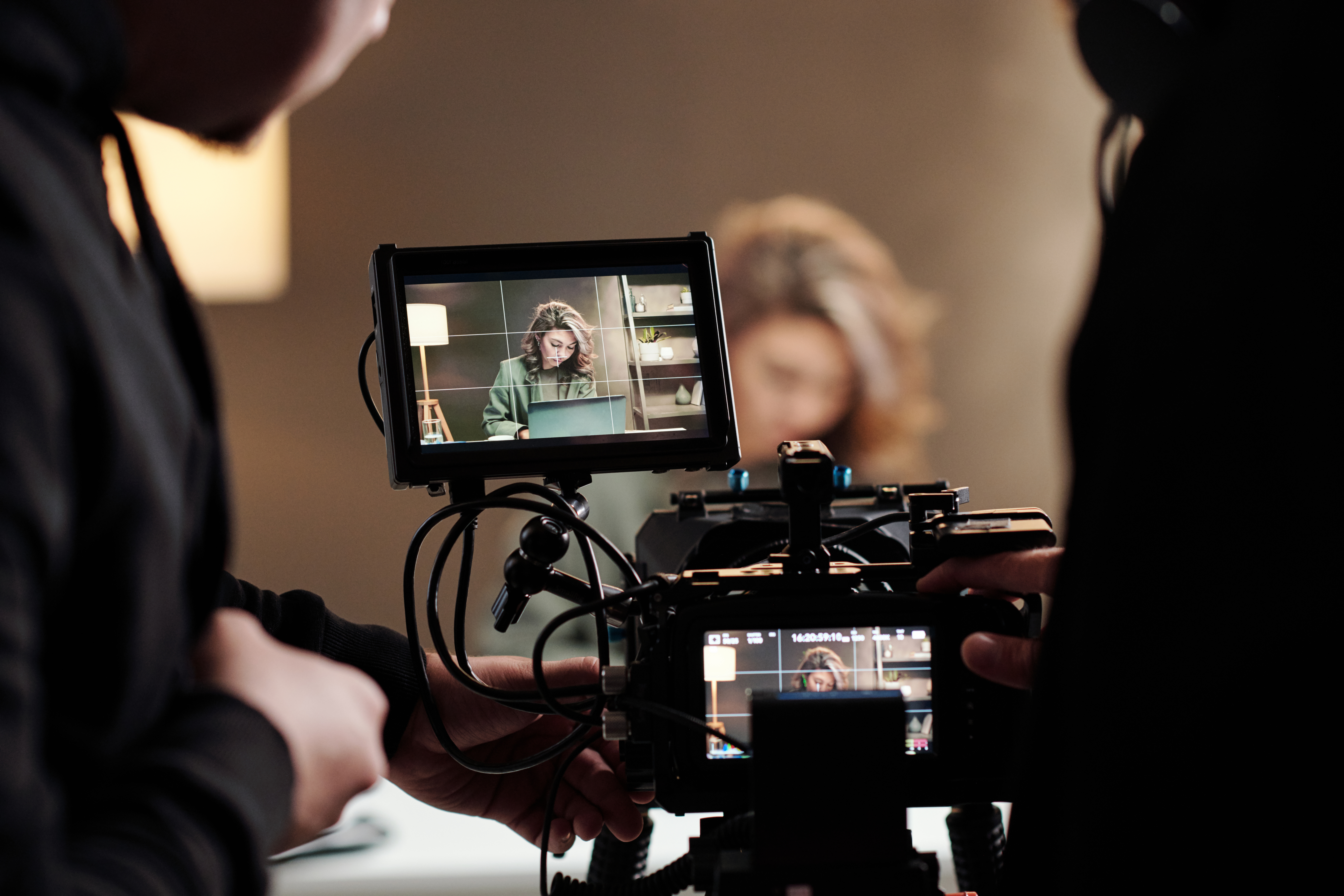 A woman working on a laptop is filmed by a professional video crew.