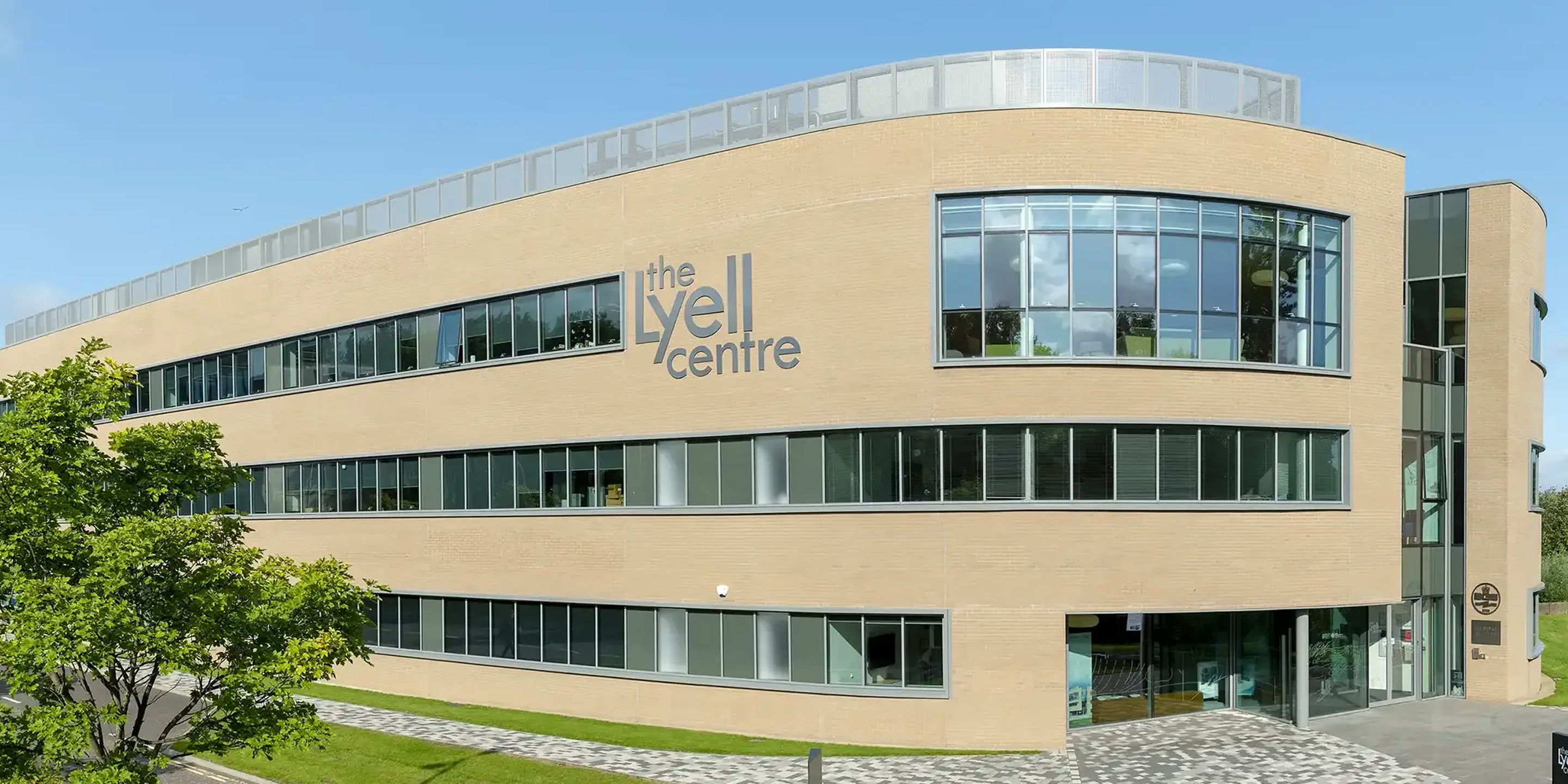 The Lyell Centre building surrounded by green lawn and trees under a blue sky.
