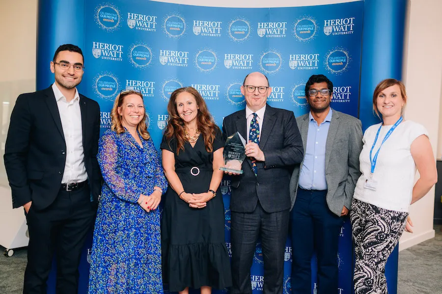Six individuals smiling as they receive an award. 