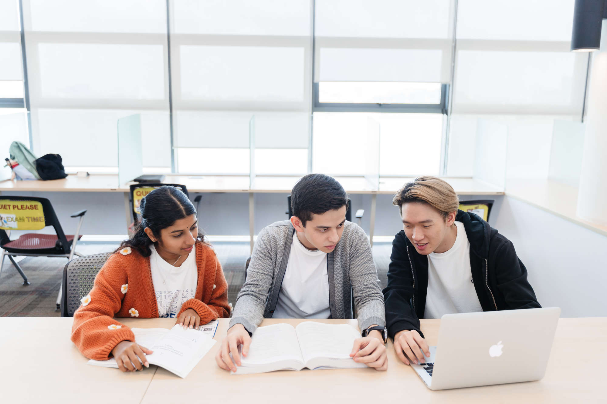 Three students sitting at a desk.
