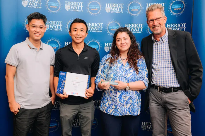 Four individuals smiling as they receive an award. 