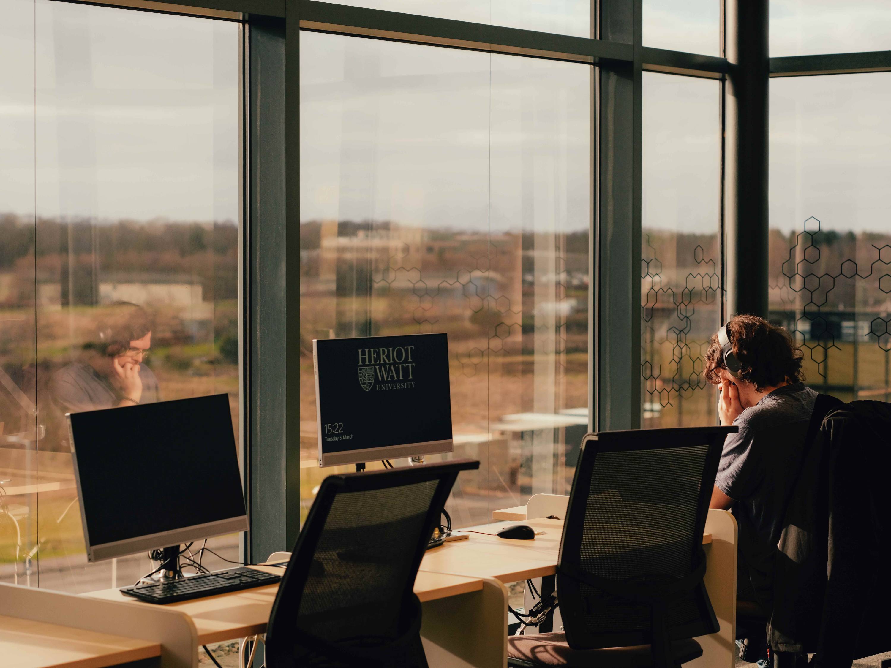 Student working at a desk infront of a window in the Edinburgh campus.