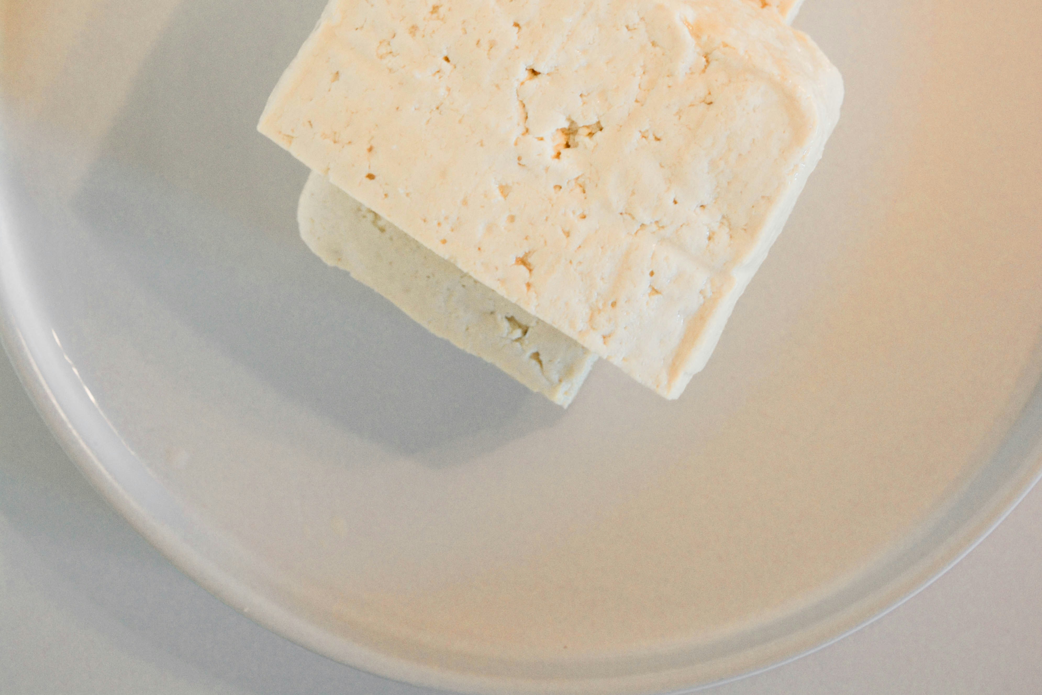 Slice of cheese pictured on a white plate.