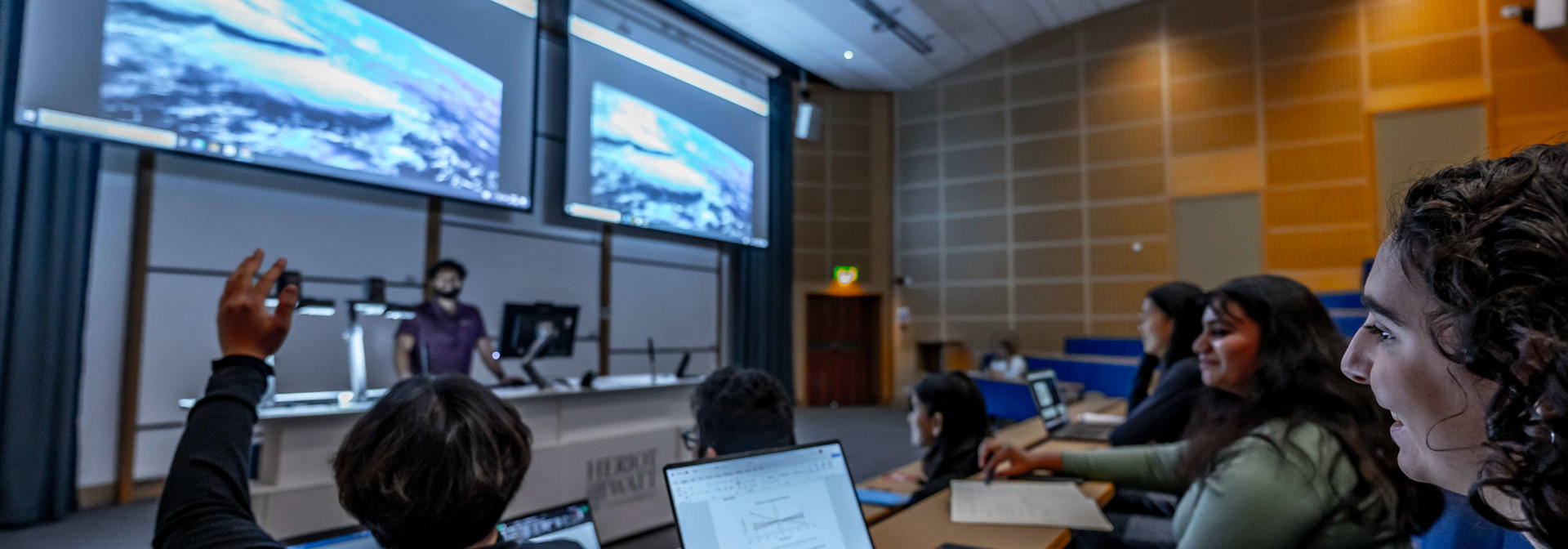 A student raises his hand to ask a question during a lecture.