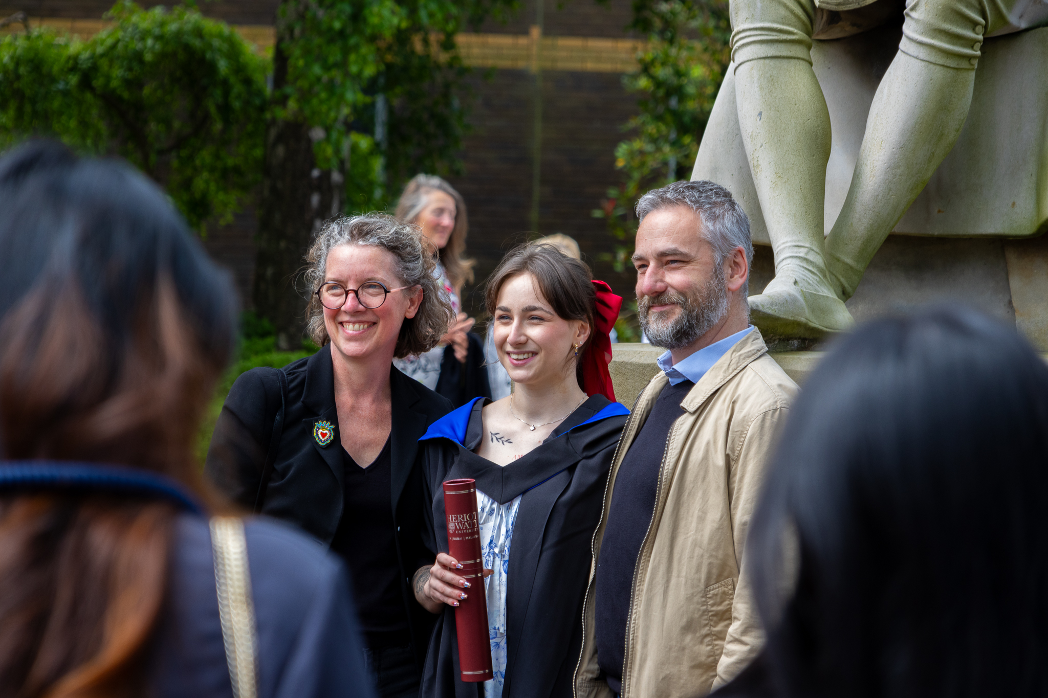 A graduate from Edinburgh campus poses for photos with their family.