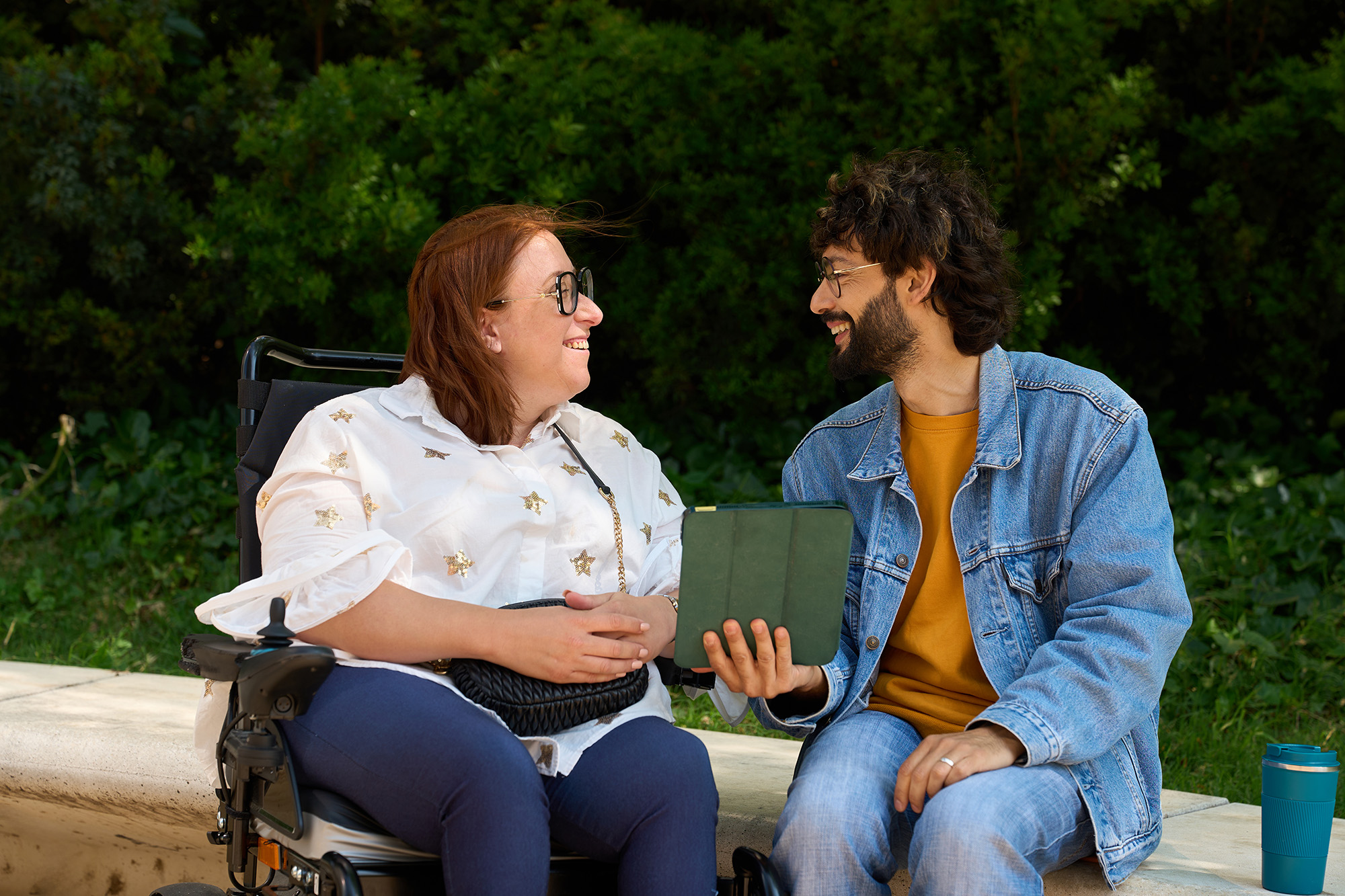 Two people smiling as they discuss over an ipad.