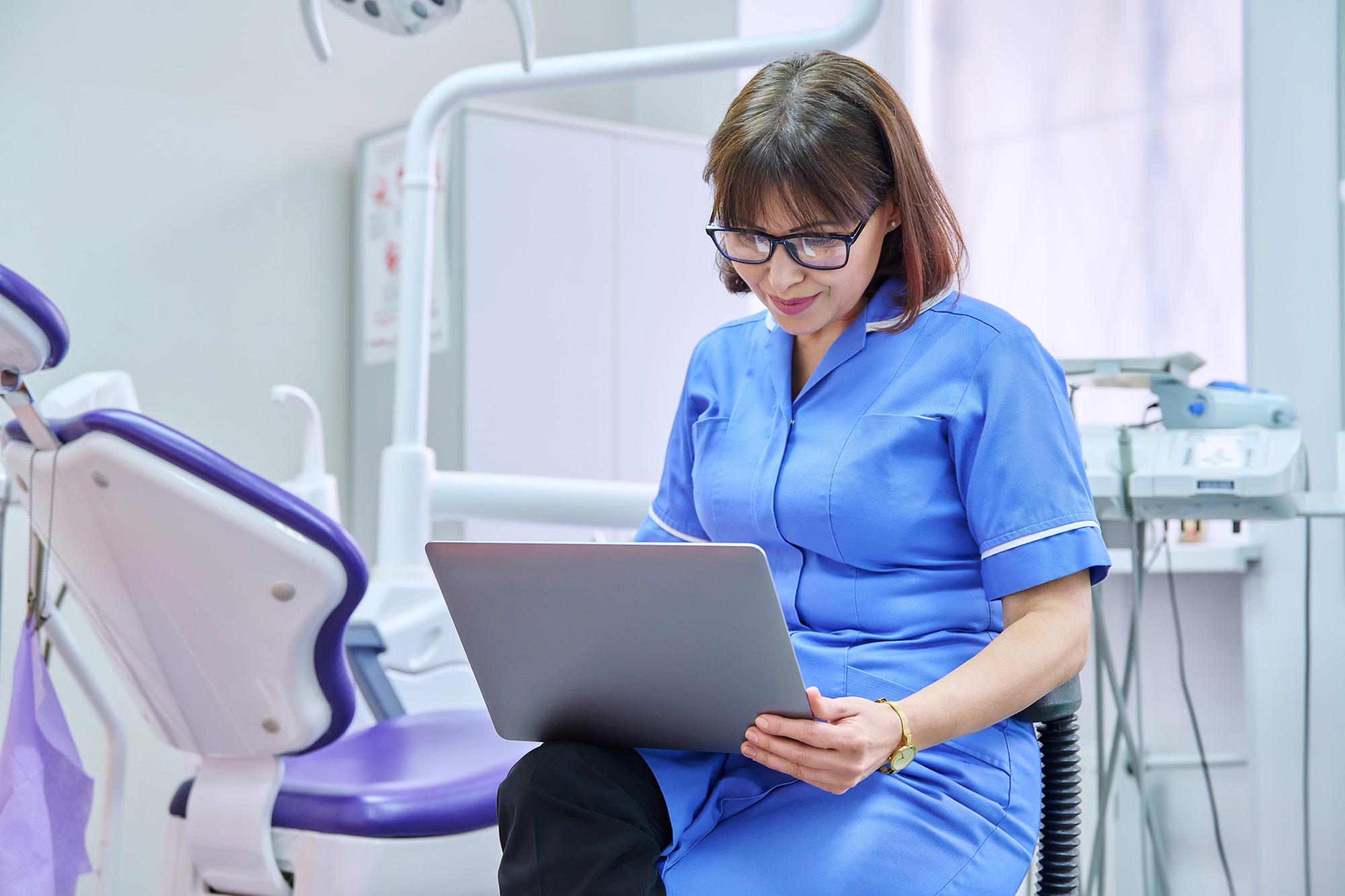 A dentist working on a laptop.