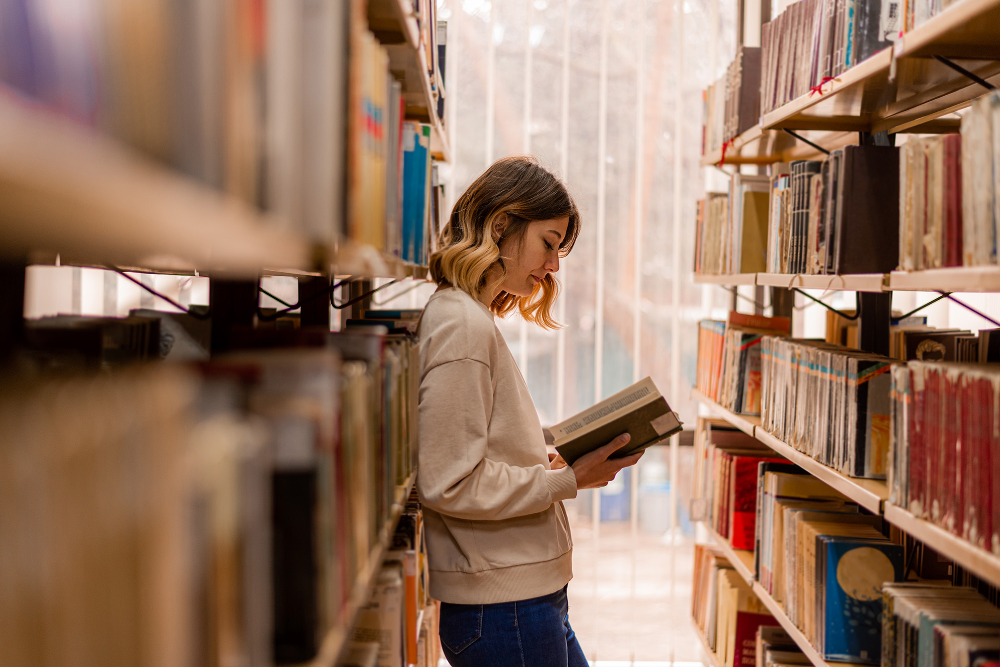 Student reading a book in a library
